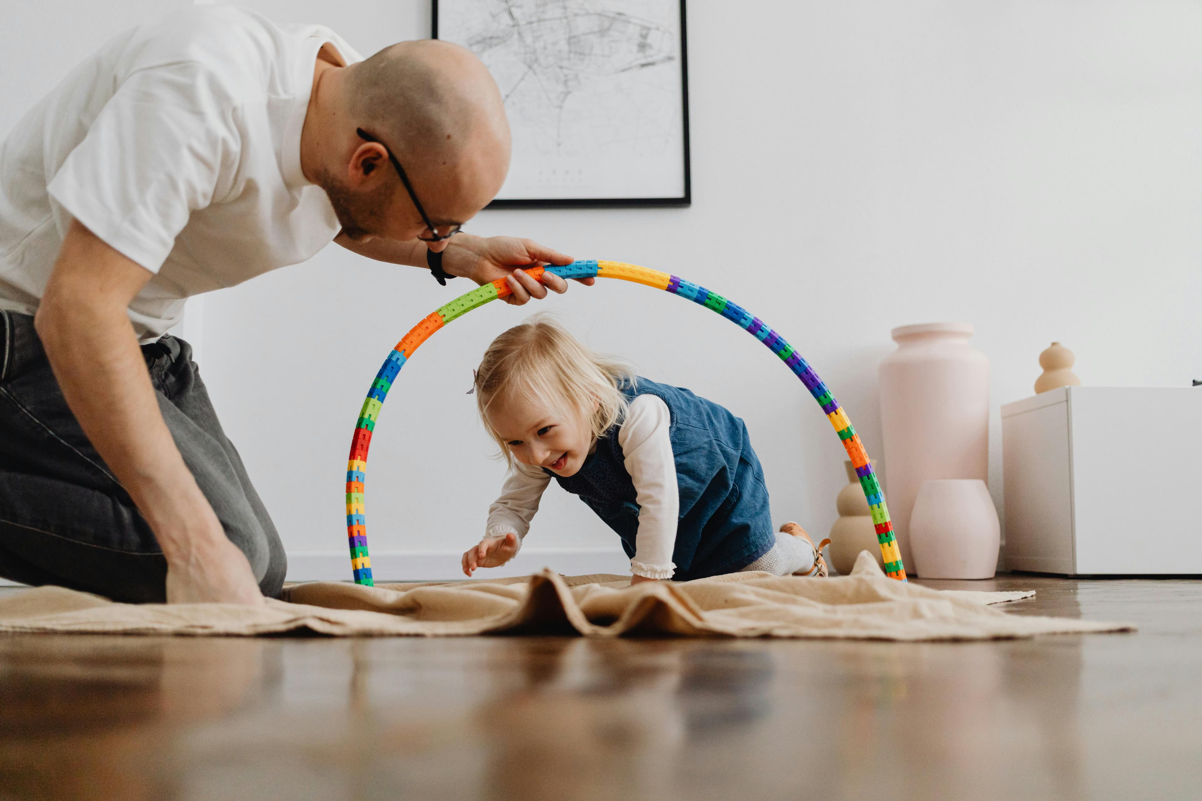 Parent holding a hoop tunnel while a toddler crawls through